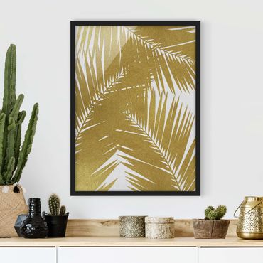 Plakat w ramie - Widok przez złote liście palmy