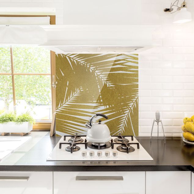 Panel szklany do kuchni Widok przez złote liście palmy